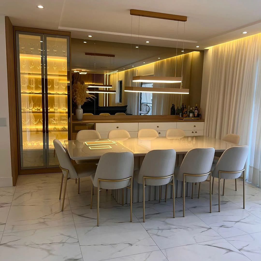 Sala de jantar planejada com cristaleira iluminada LED, buffet com espelho, mesa para 10 lugares e luminária pendente dourada – projeto residencial Estillo Design Zona Leste SP